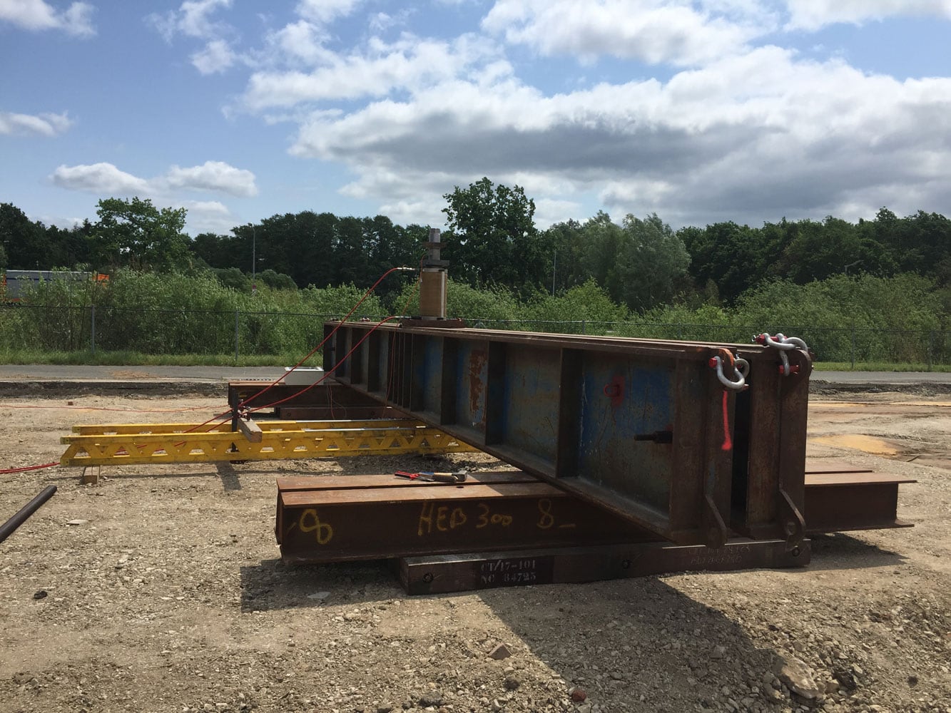 Pile load test set up with reaction beam and hydraulic jack.